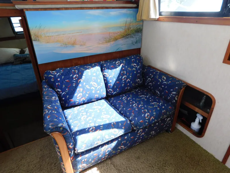 Slide: The Image of 1985 Carver 3607 Aft Cabin interior with blue patterned sofa and scenic wall art. - 24