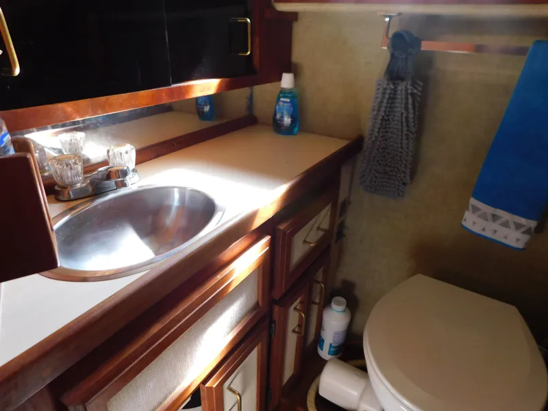 Slide: The Image of 1985 Carver 3607 Aft Cabin bathroom with sink, toilet, and storage cabinets. - 29