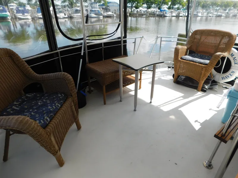 Slide: The Image of 1985 Carver 3607 Aft Cabin boat interior with wicker chairs and table, docked by the water. - 7