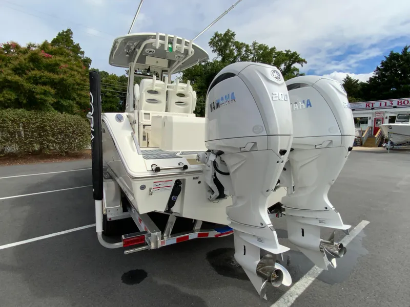 Slide: The Image of 2025 Cobia 265 Center Console Open with twin Yamaha engines in a parking lot. - 7