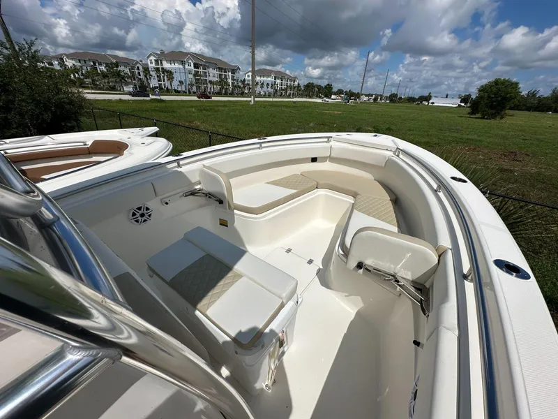 Slide: The Image of 2025 Bulls Bay 255 CC boat interior with seating and open deck under a cloudy sky. - 6