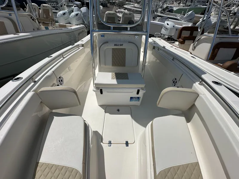 Slide: The Image of 2025 Bulls Bay 255 CC boat interior with seating and storage, docked among other boats. - 7