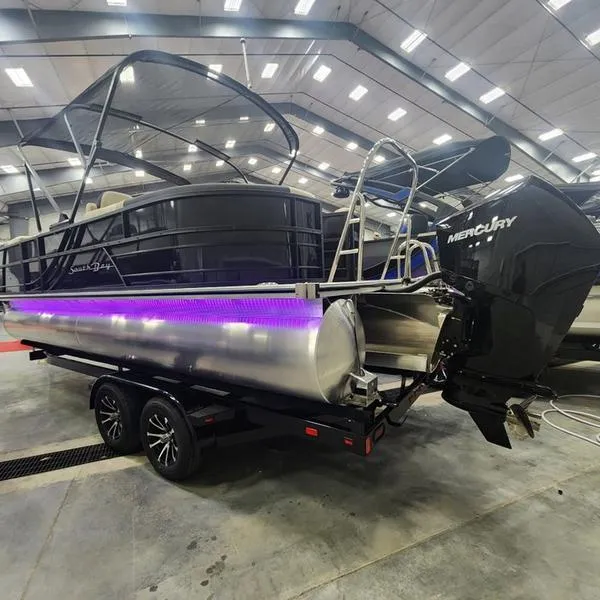 Slide: The Image of 2024 South Bay S224RS 3.0 pontoon boat with Mercury engine, displayed indoors. - 3