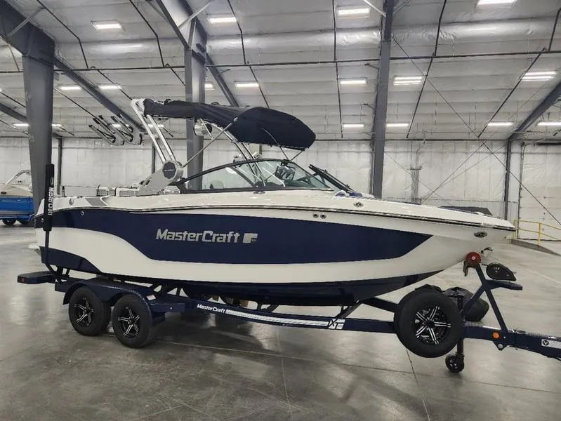 Slide: The Image of 2023 MasterCraft XT22-T boat in a warehouse on a trailer. - 1