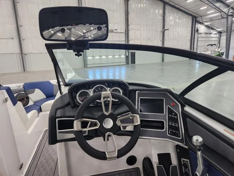 Slide: The Image of 2023 MasterCraft XT22-T boat dashboard with steering wheel and control panel in a spacious warehouse. - 11