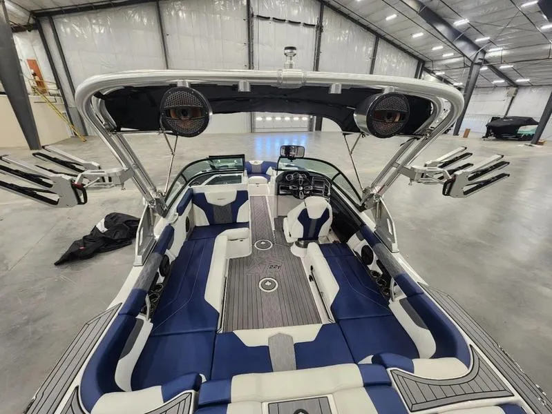 Slide: The Image of 2023 MasterCraft XT22-T boat interior with blue and white seating in a spacious warehouse. - 21