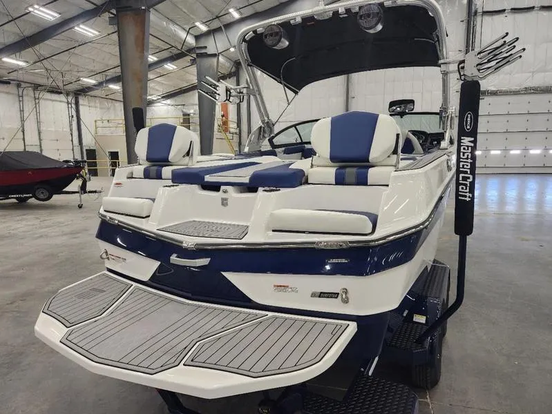 Slide: The Image of 2023 MasterCraft XT22-T boat in a spacious indoor showroom. - 27