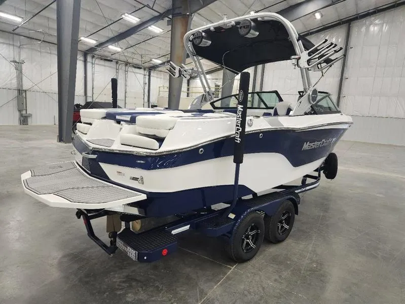 Slide: The Image of 2023 MasterCraft XT22-T boat in a warehouse, featuring sleek design and dual-axle trailer. - 3