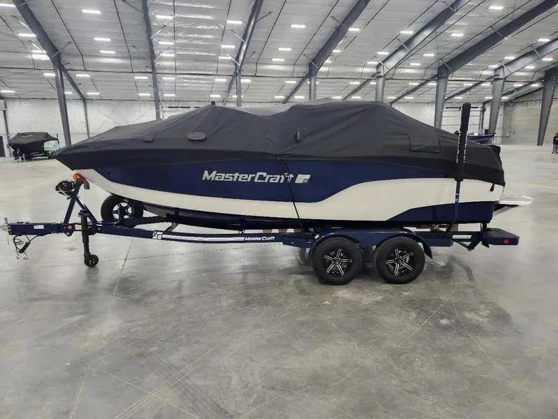 Slide: The Image of 2023 MasterCraft XT22-T boat covered on trailer in spacious indoor facility. - 33