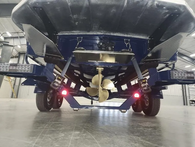 Slide: The Image of 2023 MasterCraft XT22-T boat underside with propeller and trailer in a warehouse. - 37