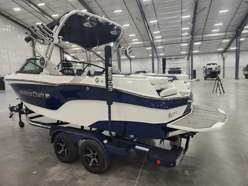 Slide: The Image of 2023 MasterCraft XT22-T boat in a spacious indoor showroom. - 4