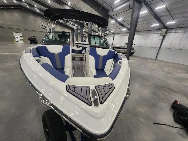 Slide: The Image of 2023 MasterCraft XT22-T boat with blue and white interior in a spacious showroom. - 6
