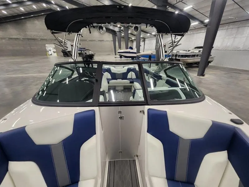 Slide: The Image of 2023 MasterCraft XT22-T boat interior with blue and white seating in a showroom. - 8