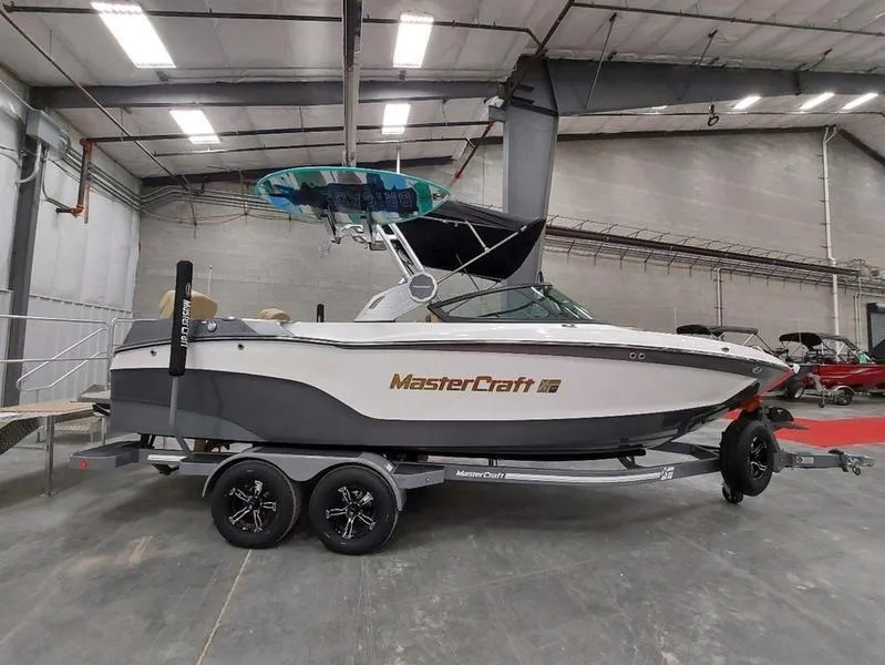 Slide: The Image of 2023 MasterCraft XT23 boat on trailer in indoor showroom. - 1