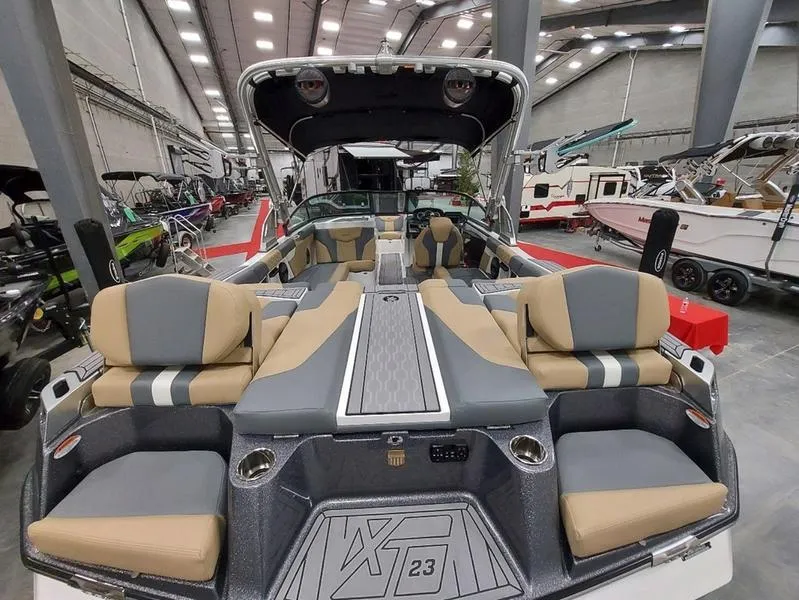 Slide: The Image of 2023 MasterCraft XT23 boat interior with luxurious seating in a showroom. - 12