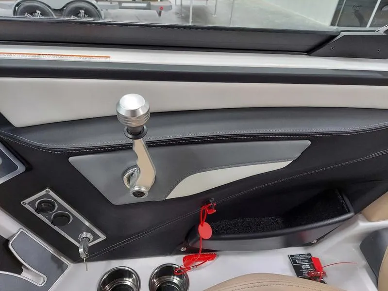 Slide: The Image of 2023 MasterCraft XT23 boat interior with control lever and cup holders. - 23