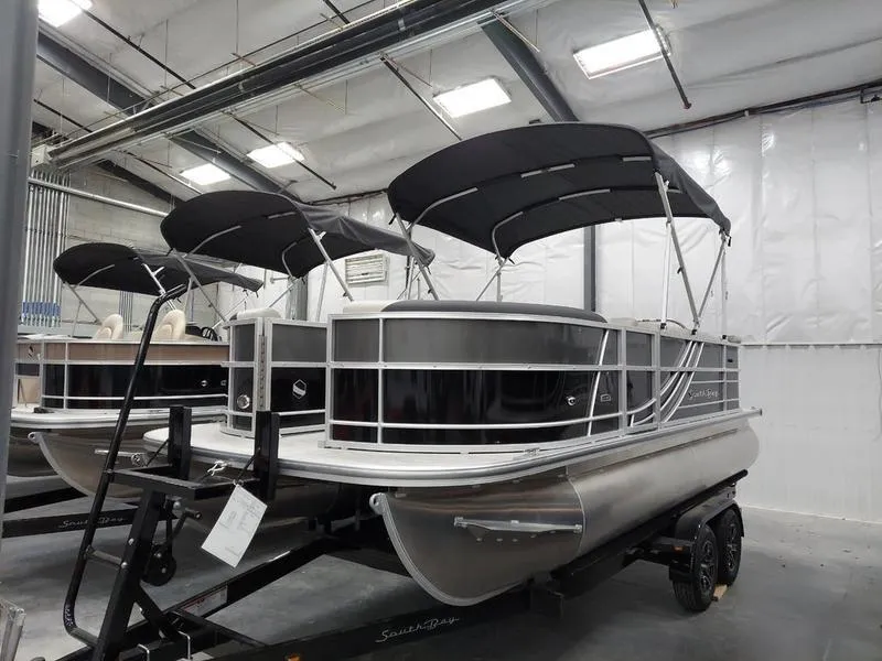 Slide: The Image of 2023 South Bay 220CR LE 25" pontoon boat in showroom with black canopy. - 1