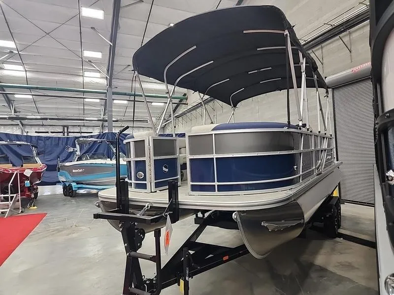 Slide: The Image of 2023 South Bay 224RS LE pontoon boat in showroom, blue and white design. - 6