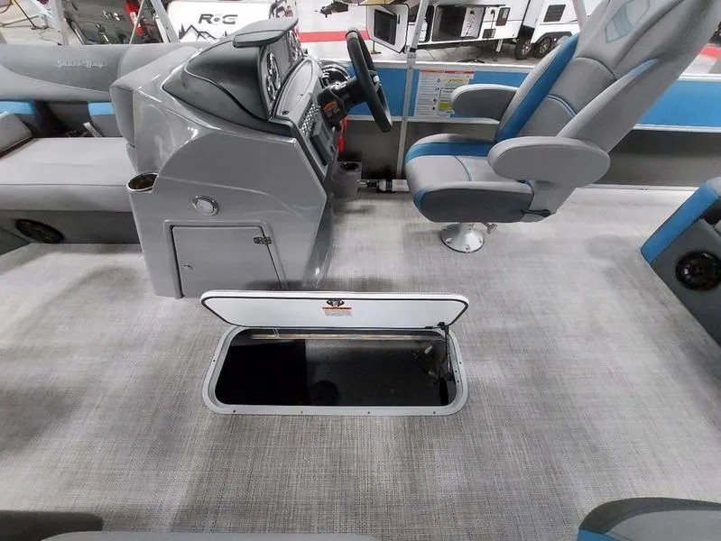 Slide: The Image of 2023 South Bay S224 UL 3.0 boat interior with open storage compartment and captain's chair. - 17