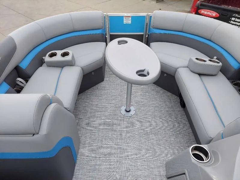Slide: The Image of 2023 South Bay S224 UL 3.0 pontoon boat interior with gray and blue seating, central table. - 23