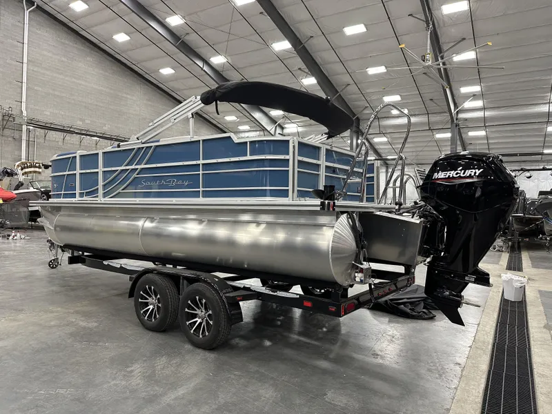 Slide: The Image of 2025 South Bay 222FCRLE pontoon boat in a warehouse, featuring a Mercury outboard motor. - 3