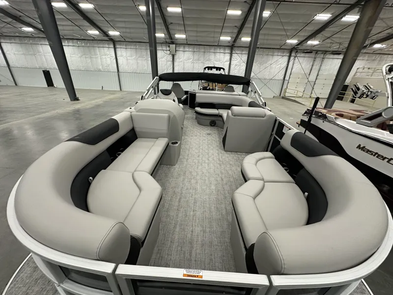 Slide: The Image of 2025 South Bay 224FCRLE pontoon boat with spacious seating in a warehouse setting. - 5