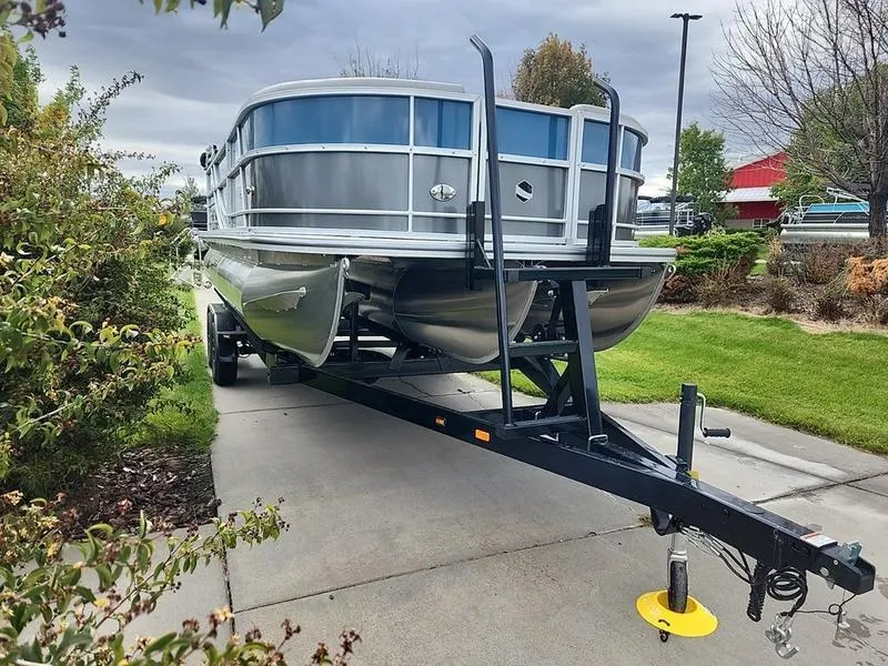 Slide: The Image of 2024 South Bay 222RS LE 2.75 pontoon boat on trailer, parked on driveway. - 1