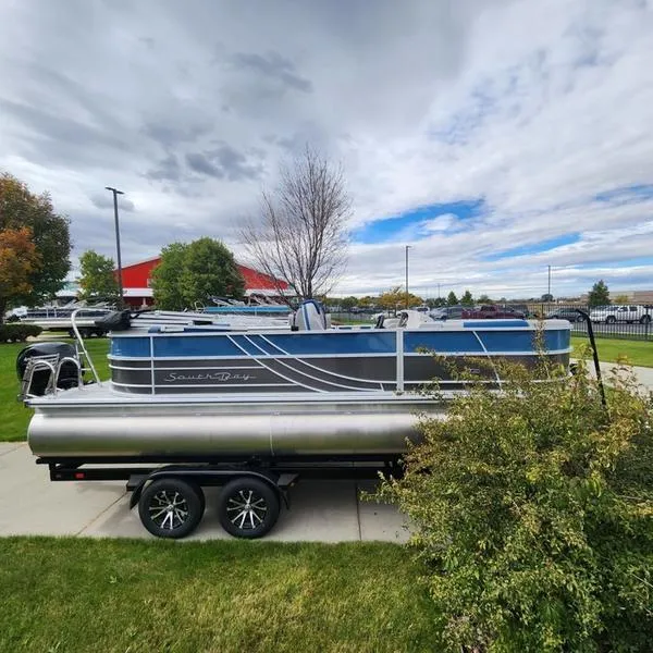 Slide: The Image of 2024 South Bay 222RS LE 2.75 pontoon boat on trailer, parked outdoors. - 2