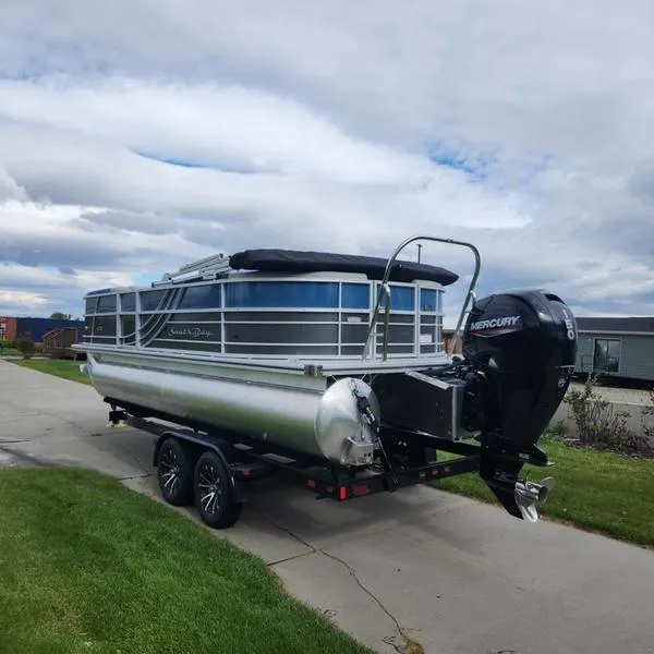 Slide: The Image of 2024 South Bay 222RS LE 2.75 pontoon boat on trailer, parked on a driveway. - 6