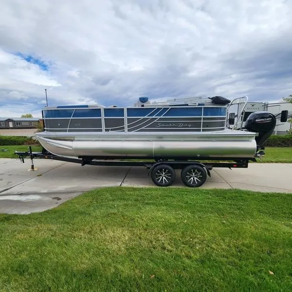 Slide: The Image of 2024 South Bay 222RS LE 2.75 pontoon boat on trailer, parked on driveway. - 7