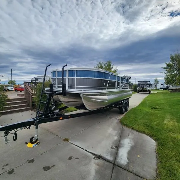 Slide: The Image of 2024 South Bay 222RS LE 2.75 pontoon boat on trailer, parked on driveway. - 8
