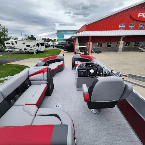 Slide: The Image of 2024 South Bay S224FCR 2.75 pontoon boat with red and gray seating, parked near a dealership. - 14