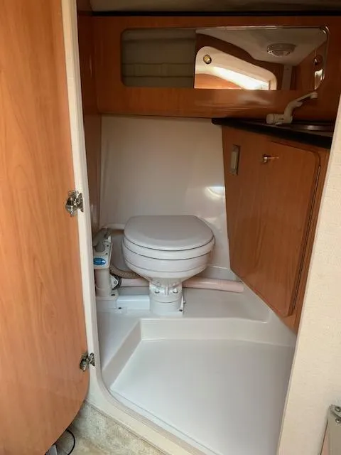 Slide: The Image of 1999 Regal 2850 LSC boat bathroom with toilet, sink, and wooden cabinetry. - 12
