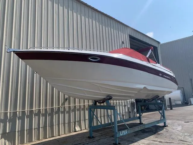 Slide: The Image of 1999 Regal 2850 LSC boat with red cover on a stand outside a warehouse. - 14