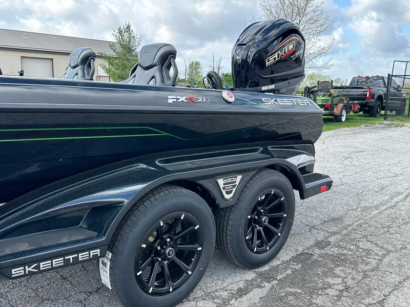 Slide: The Image of 2024 Skeeter FXR21 LE boat on trailer with dual wheels, parked outdoors. - 9