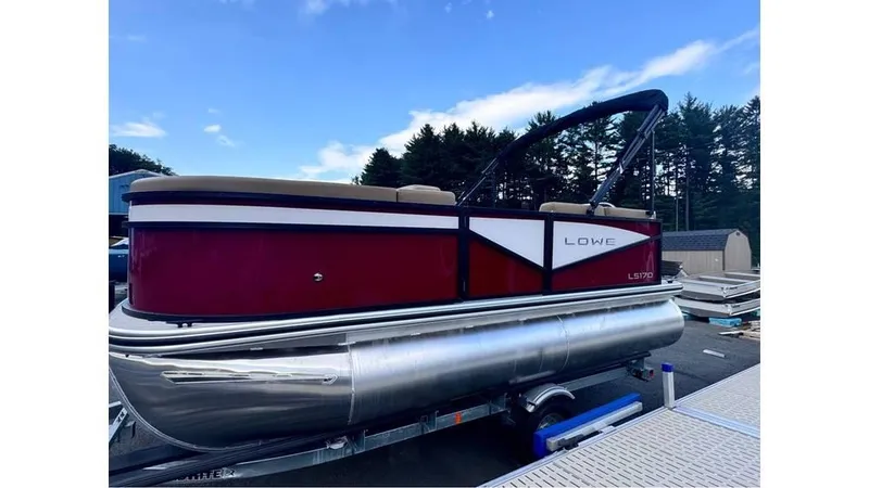 Slide: The Image of 2025 Lowe LS170 pontoon boat on trailer, red and white design, parked outdoors. - 4