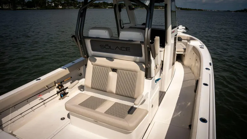 Slide: The Image of 2025 Solace 28 HCS boat interior with cushioned seating on calm water. - 10