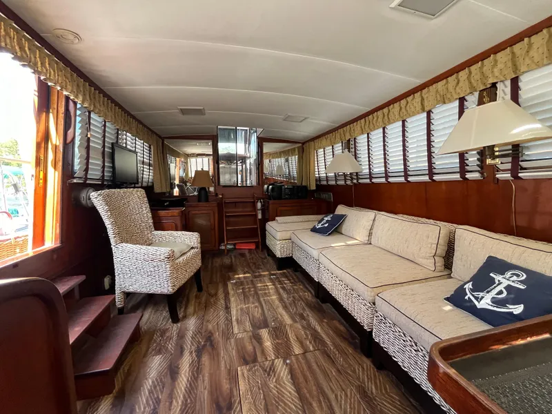 Slide: The Image of 1980 Gulfstar Trawler interior with wood flooring, beige seating, nautical decor, and ample natural light. - 14