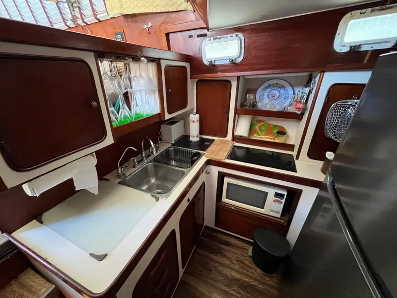 Slide: The Image of 1980 Gulfstar Trawler kitchen with wooden cabinets, sink, stove, and microwave. - 15