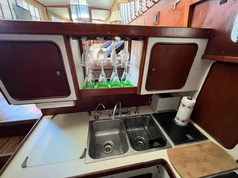 Slide: The Image of 1980 Gulfstar Trawler kitchen with sink, cabinets, and hanging glasses. - 16