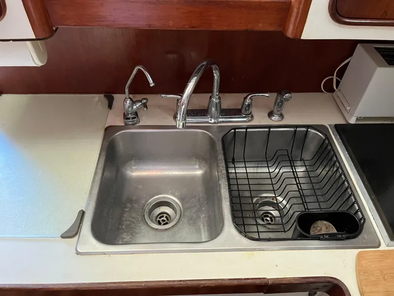 Slide: The Image of 1980 Gulfstar Trawler kitchen sink with dual faucets and drying rack. - 17