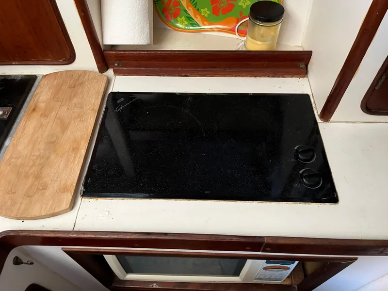 Slide: The Image of 1980 Gulfstar Trawler kitchen with black stovetop and wooden cutting board. - 18