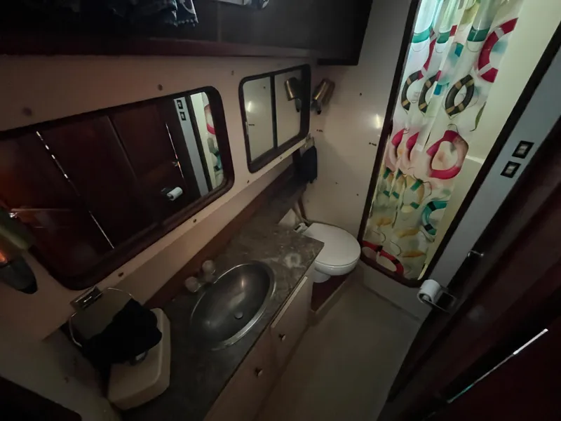 Slide: The Image of 1980 Gulfstar Trawler bathroom with sink, toilet, and colorful shower curtain. - 24