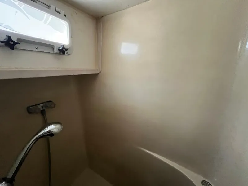 Slide: The Image of 1980 Gulfstar Trawler bathroom with showerhead and small window. - 27