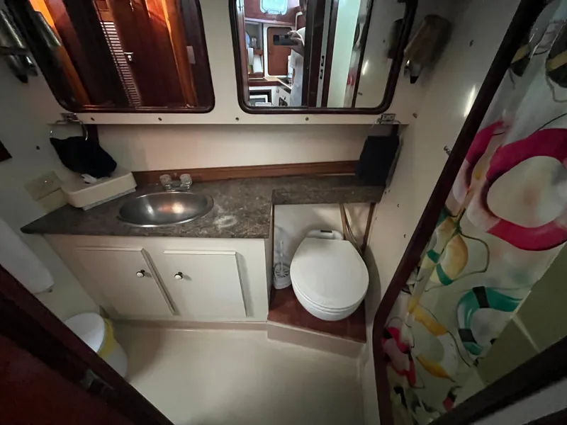 Slide: The Image of 1980 Gulfstar Trawler bathroom with sink, toilet, and colorful shower curtain. - 29