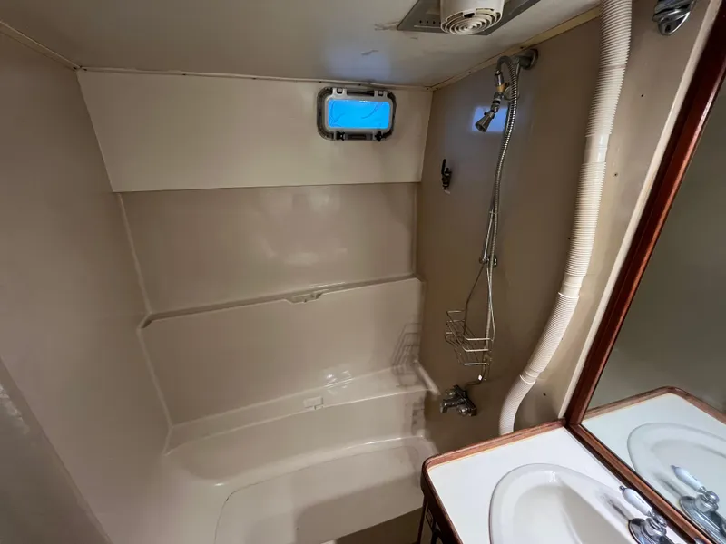 Slide: The Image of 1980 Gulfstar Trawler bathroom with shower, sink, and small window. - 37