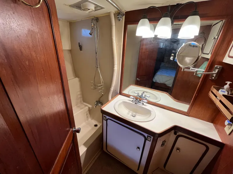 Slide: The Image of 1980 Gulfstar Trawler bathroom with shower, sink, mirror, and wooden cabinetry. - 38