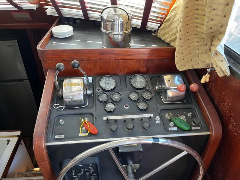 Slide: The Image of 1980 Gulfstar Trawler helm with gauges, controls, and steering wheel in a wooden cabin interior. - 5