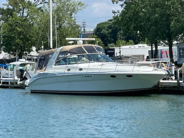 Slide: The Image of 1999 Sea Ray 400 Sundancer yacht docked in a marina, surrounded by trees and water. - 0