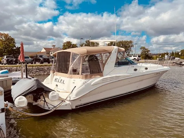Slide: The Image of 1999 Sea Ray 400 Sundancer yacht docked in a marina under a partly cloudy sky. - 1